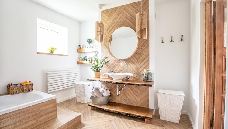 White sink on wood counter with a round mirror hanging above it. Bathroom interior.