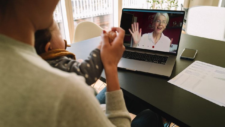 Woman with her daughter having video call with her mother. Woman connecting with her mother on a video call while at home.