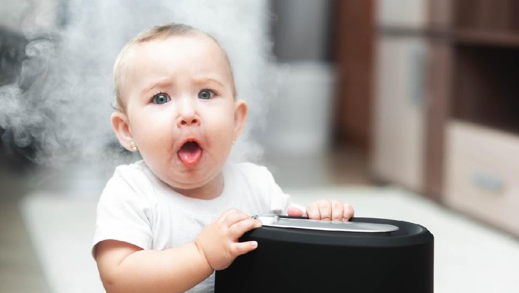 The baby looks at the humidifier. Moisture in the home healthy air concept