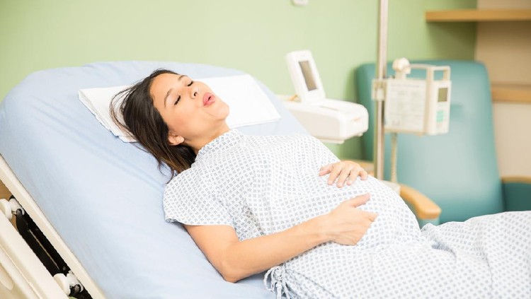 Portrait of a beautiful young pregnant woman trying to breath to soothe the pain of her labor contractions in a hospital