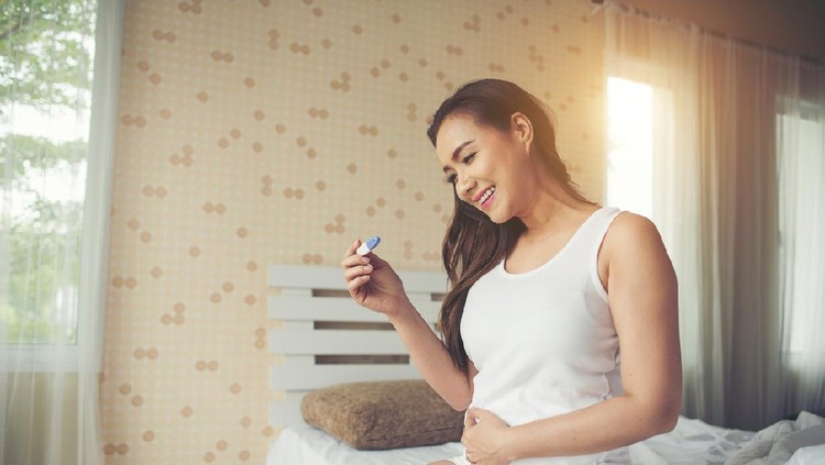 close-up of smiling woman holding pregnancy test