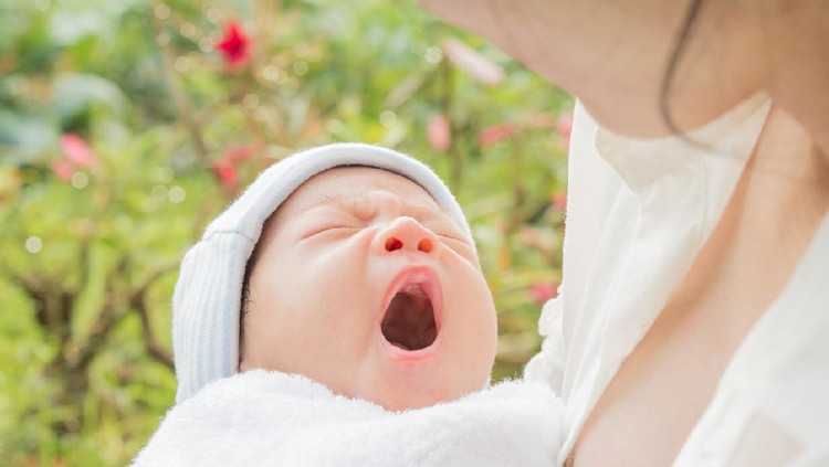 Baby sleeps on mother's hands and morning sun