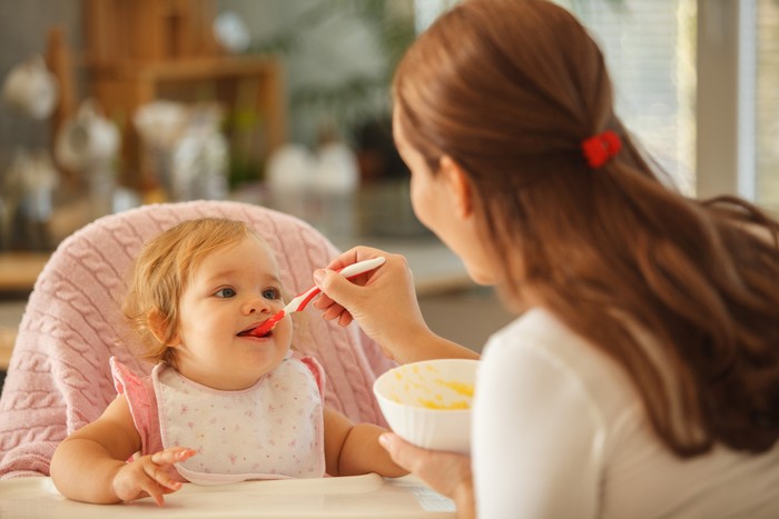 Close-up shot of mother spoon feeding her baby girl.