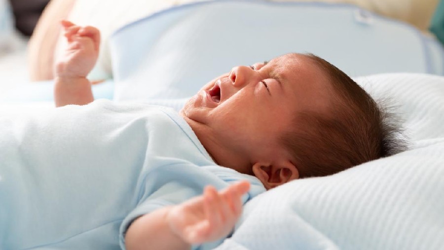 Profile shot of little baby taking medicine from the spoon in mothers hand.