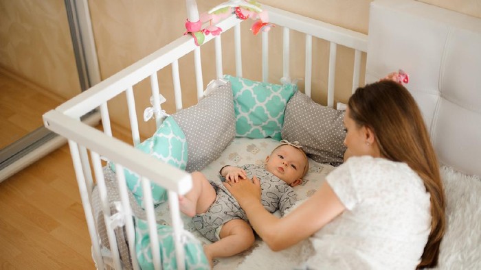 Tired mother holding her newborn child at home after tying to pump.