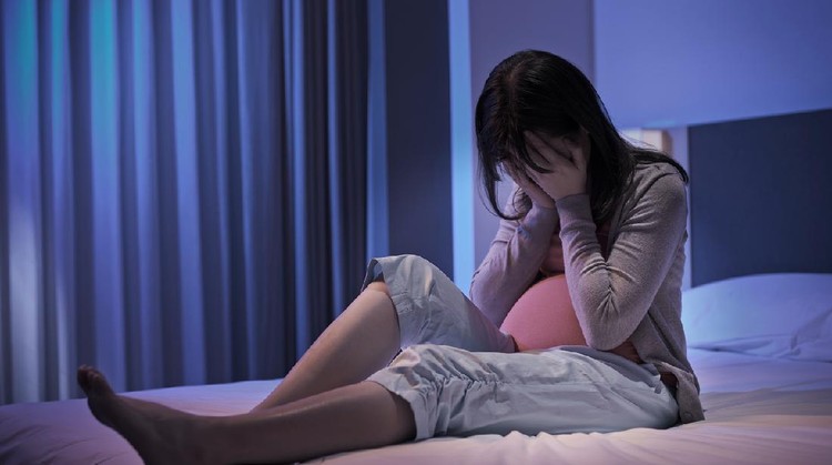 pregnant woman sit on the bed and feel depression at home