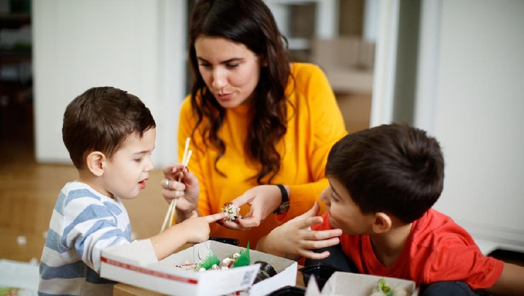 Ilustrasi ibu dan anak Mother offering take out sushi roll to her toddler disgusted with its looks, they are using cardboard box as table at time of moving house