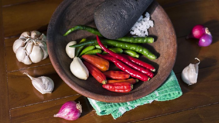 Basic ingredients to make traditional sambal; chilli pepper, garlic, onion, and salt is prepped on wooden cobek.

(Indonesia) - Bahan sambal tradisional: cabe rawit, cabe merah, bawang putih di atas cobek kayu.
