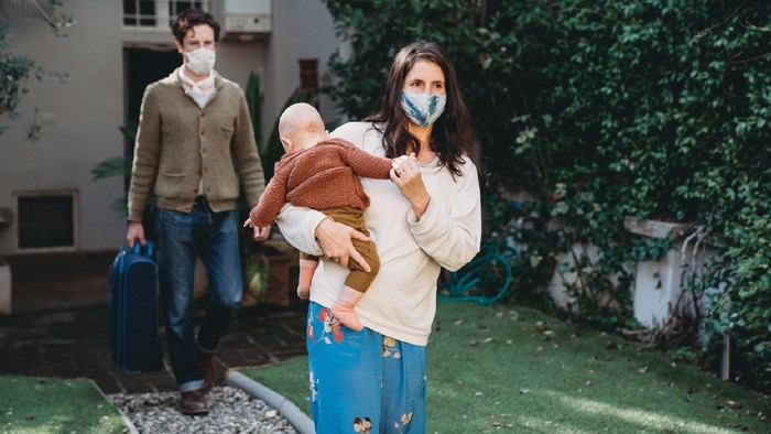 Family with one child traveling during Covid-19, wearing protective face masks. They are arriving at a bed and breakfast.