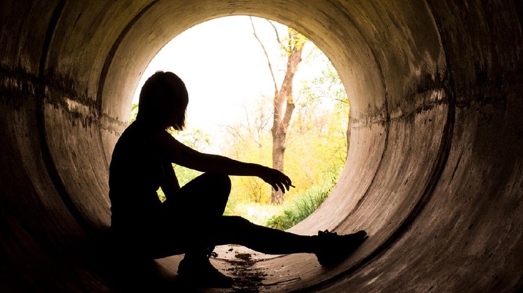 Silhouette of a young girl smoking in sewer pipe