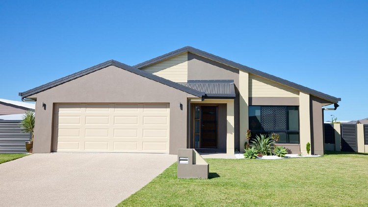 Front of a new modern single story family home with green grass and clear blue sky for copy space.