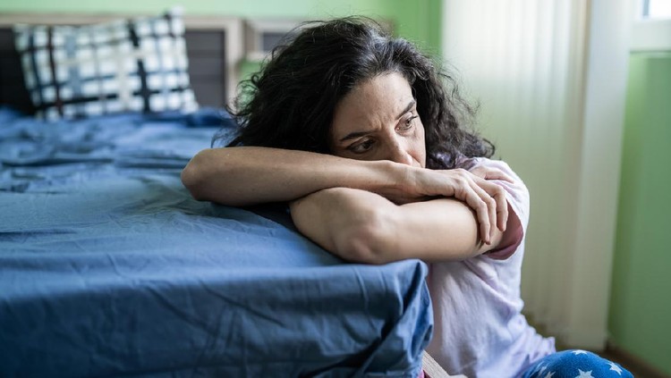 Mid adult woman sitting home alone, worried.
