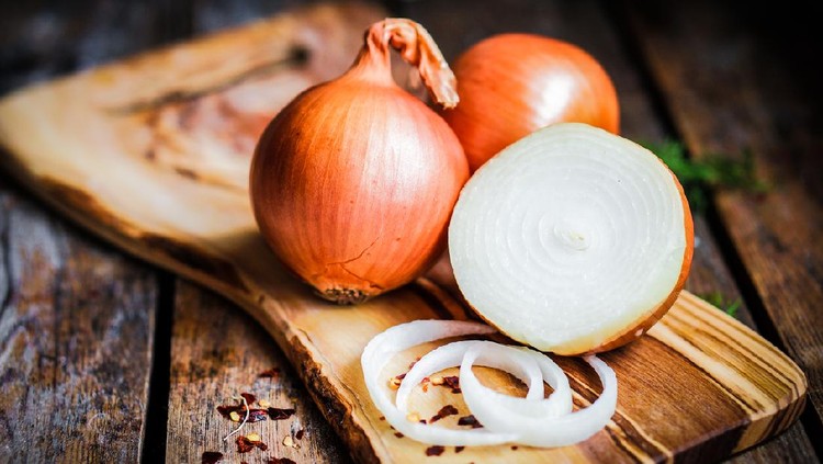 Golden onions on rustic wooden background