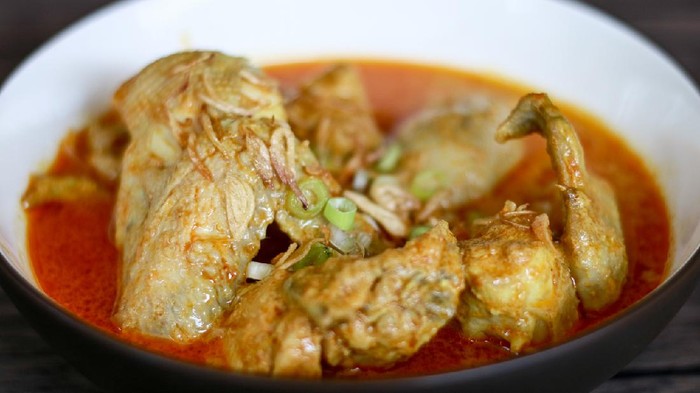 Indonesian gulai ayam or Indonesian chicken curry in a bowl on wood background.