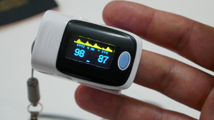 Woman hand introduced in a oximeter to check oxygen levels and pulse because Covid-19 pandemic