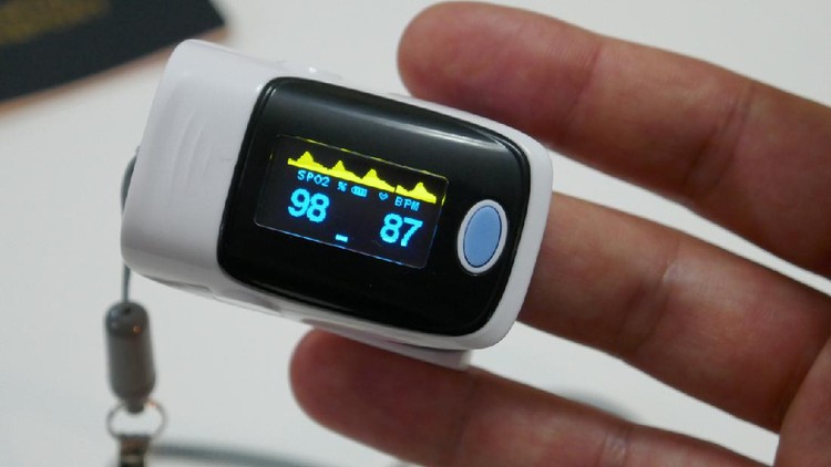 Woman hand introduced in a oximeter to check oxygen levels and pulse because Covid-19 pandemic