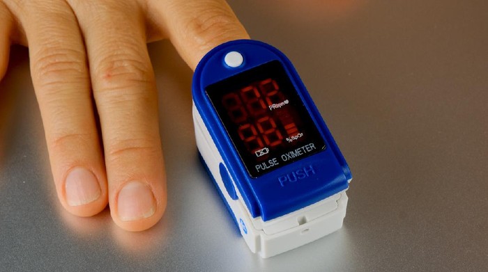 Woman hand introduced in a oximeter to check oxygen levels and pulse because Covid-19 pandemic