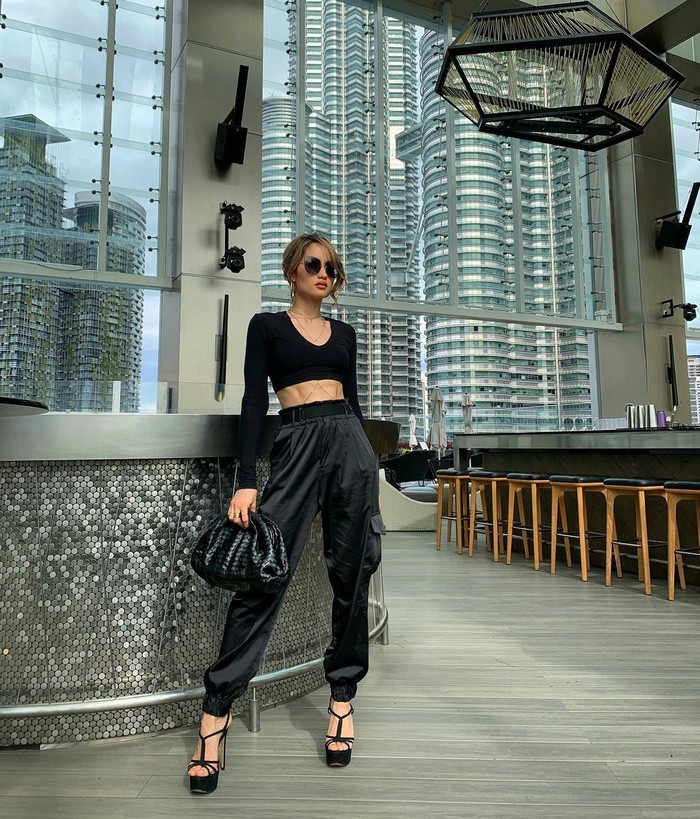 'All black outfit' tak hanya dipakai dalam kesempatan formal. Cinta memadukan pakaian hingga aksesoris serba hitam untuk tampil kasual dan feminin. Dia memadukan jogger pants dan long sleeve shirt crop top polos, heels, handbag dan sunglasses dalam potretnya kali ini/Sumber/Instagram/claurakiehl.