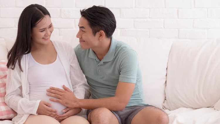 940751088 Pregnant women with her husband feeling happy, father is touching to the baby in mother's womb.