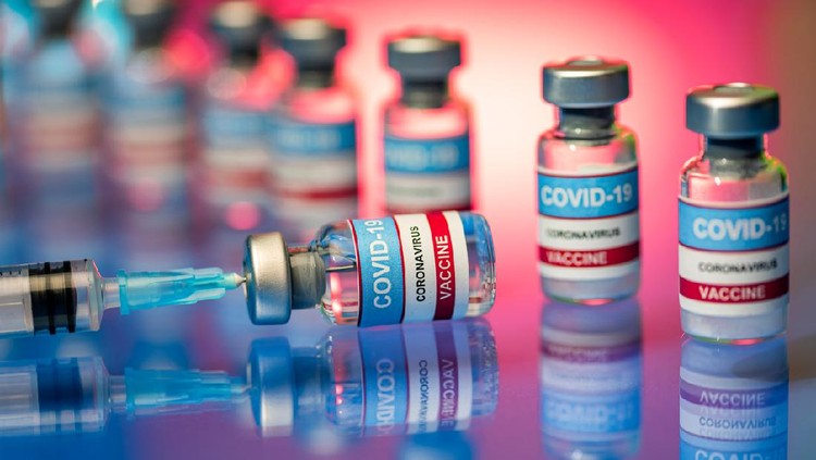 Close up of Covid-19 vaccine - vials and syringe. Glass bottles on a reflective surface