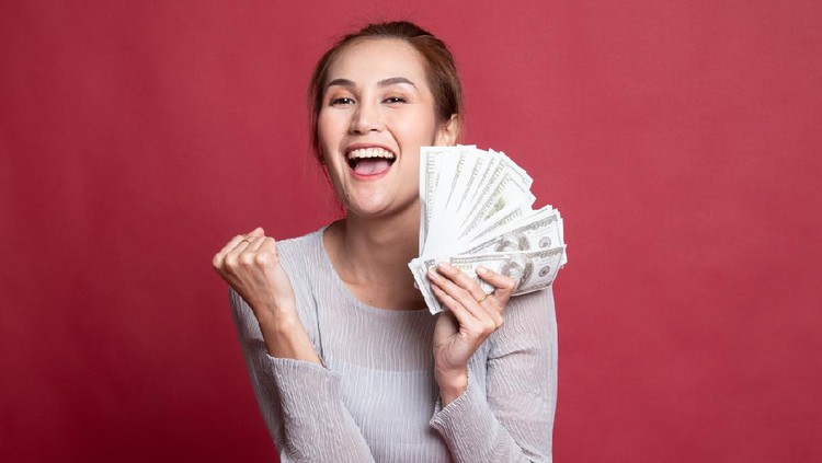 Portrait of  young asian woman  showing bunch of money banknotes on red background