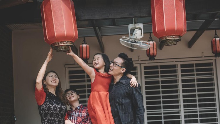 an asian chinese family in malaysia fixing their red lanterns for chinese new year preparation in front of their house