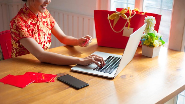 Asian women in cheongsam are carrying credit cards and online shopping. The concept of shopping and giving gifts or gift vouchers online during the Chinese New Year festival.