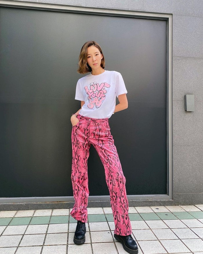 Pilihan pakaian pink gak hanya untuk atasan, kali ini Irene memakainya untuk celana, bahkan dengan motif kulit ular. Dia memadukannya dengan t-shirt putih yang memiliki tulisan warna pink, serta memakai boots hitam/Sumber/Instagram/ireneisgood.