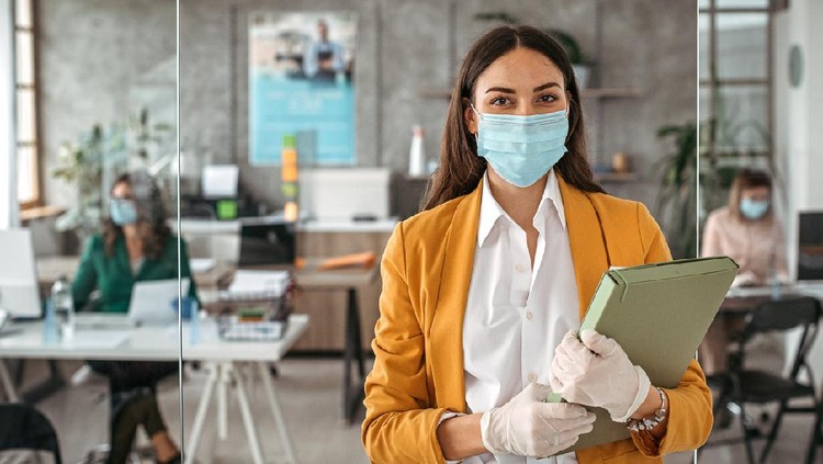Portrait of businesswoman with protective gloves and face mask after returning back to work at office