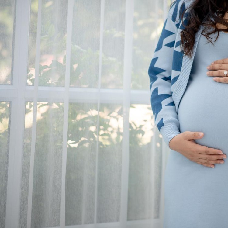 1199384074 Beautiful young women in the third trimester of pregnancy Pregnant woman holding arms in her stomach Expecting child concepts White background