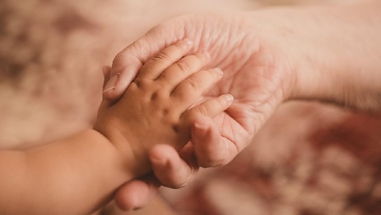 Grandmother holding little grandson in the room at home. Senior woman hold little baby cute smiling. Happy grandmother with her grandchild in home.
