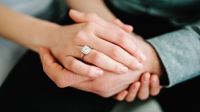 Close up of an elegant engagement diamond ring on woman finger. love and wedding concept.