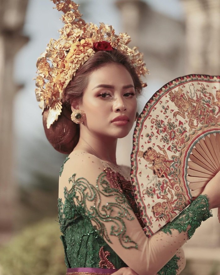 Aurelie tampak anggun dengan pakaian tradisional Bali yang cerah dengan warna hijau. Dia memakai kebaya lengkap dengan sanggul Pusung Tagel, dan aksesoris kepala Payas serta kipas/Sumber/Instagram/aurelie.hermansyah.