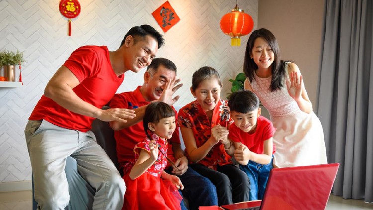 Multi-generation Chinese family greeting friends and relatives during Chinese New Year with video call on laptop computer during lockdown and MCO (movement control order) on global pandemic. Covid-19 and Coronavirus, 5G & Wireless Technology, Chinese New Year Celebration and Chinese Traditional Festival, Family Bonding and Togetherness Concepts.