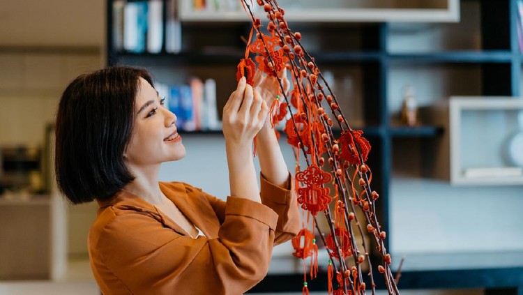 Image of an Asian Chinese woman hanging decoration on a plant and prepare for Chinese New Year