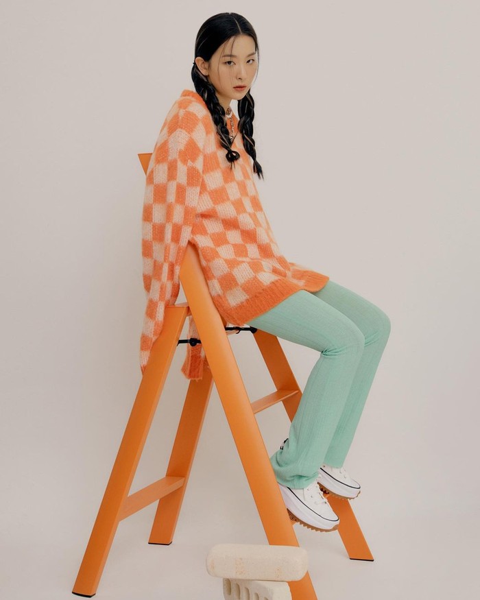 Tidak lagi tampil boyish, Seulgi menggunakan outfit yang lebih colorful, ia menggunakan roundneck knit checkered berwarna orange, celana panjang berwarna tosca, dan sepatu Converse Run Star Hike berwarna putih. (Foto: Instagram/hi_sseulgi)
