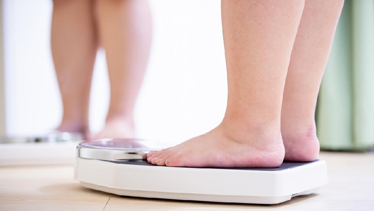 plus size asian girl look mirror and measure her weight by scale