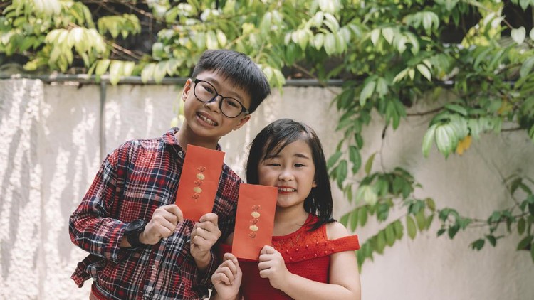 grandfather giving red packet angpao to his grandson during chinese new year's eve reunion dinner