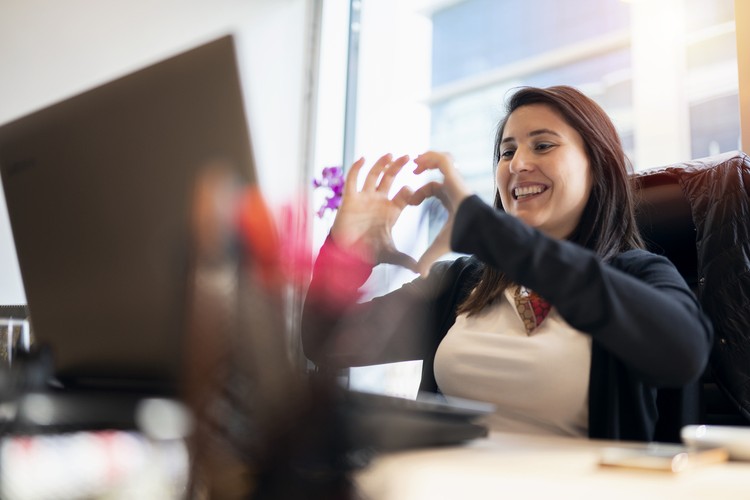 Ilustrasi Hari Valentine Woman at office video chatting, and making heart shape