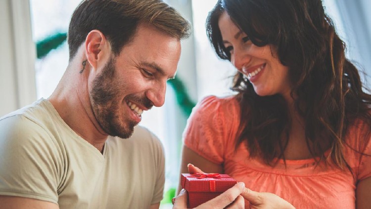 Close up of an affectionate couple sharing a gift for anniversarie where both of them smile pleasantly