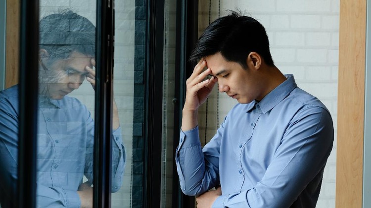 Business man Feeling exhausted massaging headache and stand at his working place in office.