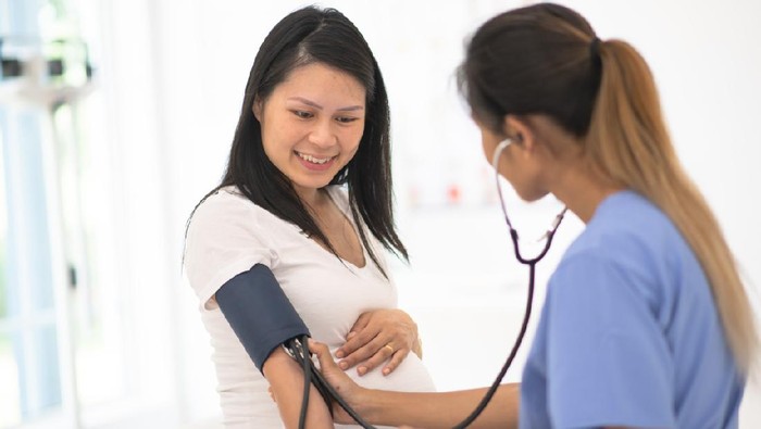 A pregnant woman has her blood pressure checked by her obstetrician at a routine prenatal appointment