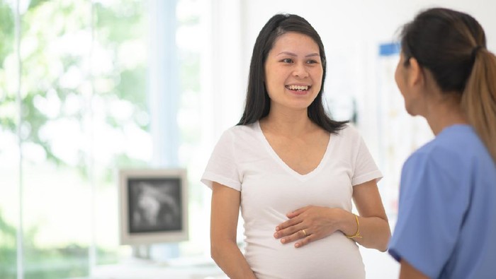 A pregnant woman has her blood pressure checked by her obstetrician at a routine prenatal appointment