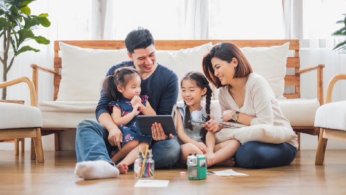 Happy Asian family using tablet, laptop for playing game watching movies, relaxing at home for lifestyle concept
