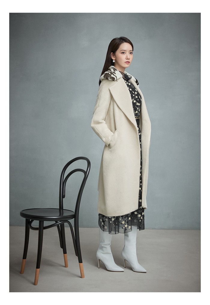 Untuk nuansa winter, Yoona tampil dengan menggunakan dress hitam panjang berbodir bunga tiga dimensi dan mantel alpaka yang lembut berwarna abu-abu sebagai outerwear. (Foto: jigott.co.kr)