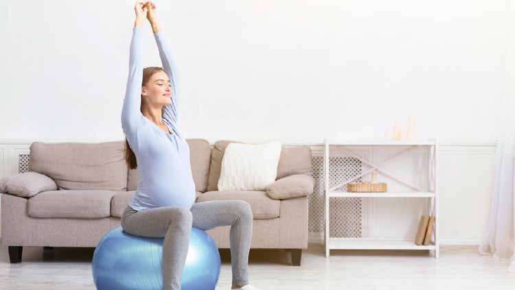 Healthy Lifestyle. Happy pregnant woman exercising on fitball at home. Free space