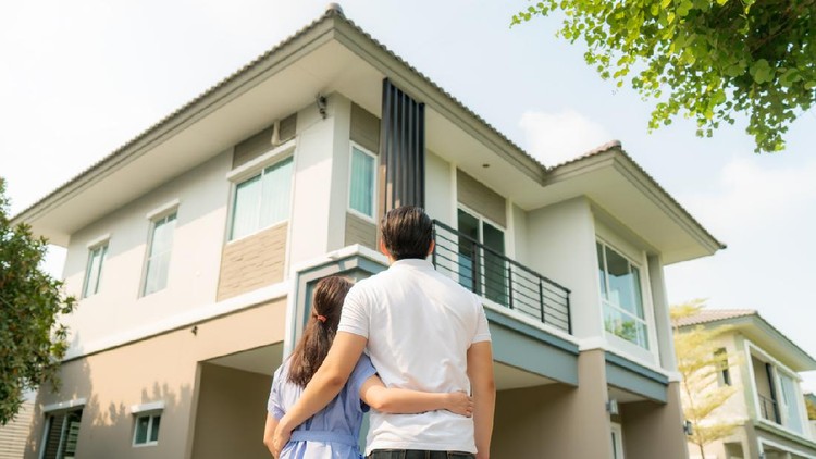 Back portrait of Asian young couple standing and hugging together looking happy in front of their new house to start new life. Family, age, home, real estate and people concept.