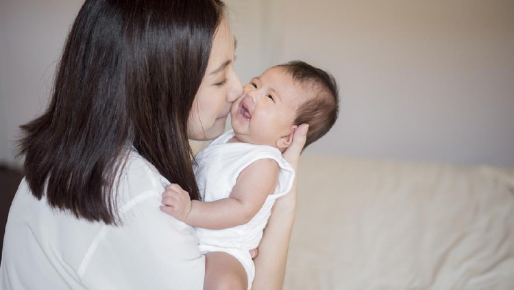 Beautiful woman holding a newborn baby in her arms