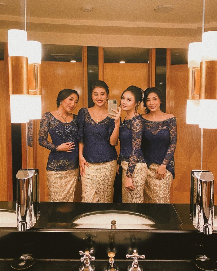 Dipilih sebagai bridesmaid, kamu bisa tampil pakai baju kondangan kembar dengan sahabat dekat seperti Awkarin. Padukan kebaya biru navy model kerah rendah dengan rok songket warna gold (Foto: www.instagram.com/awkarin/).