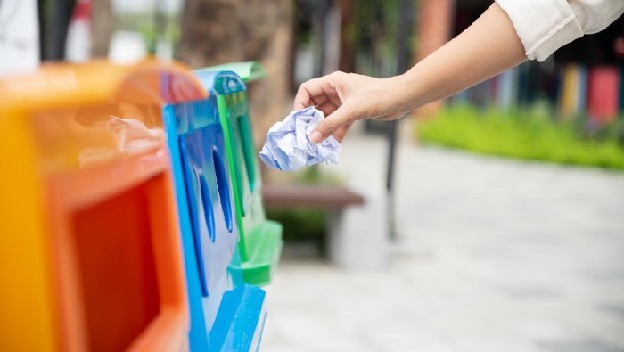 Closeup portrait woman hand throwing crumpled paper in recycling bin.